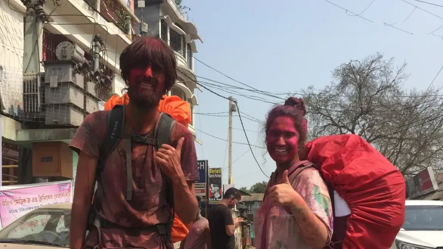Pareja con mochilas sonriendo en una calle concurrida