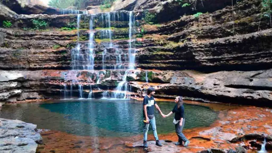Pareja de excursión junto a una cascada y una poza natural