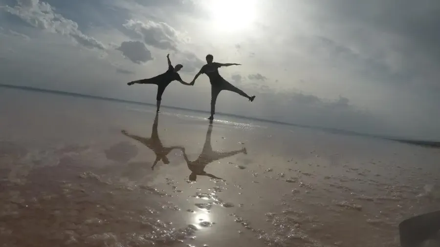 Dos personas posando sobre una superficie que refleja el cielo