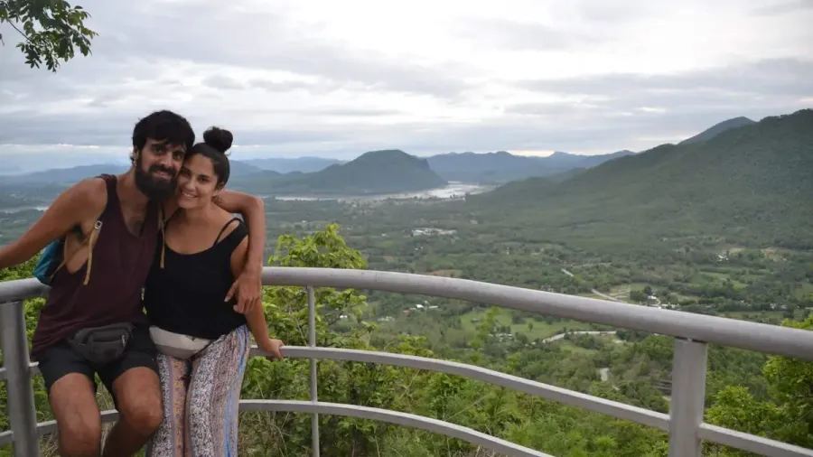 Pareja sonriendo en un mirador con montañas verdes al fondo