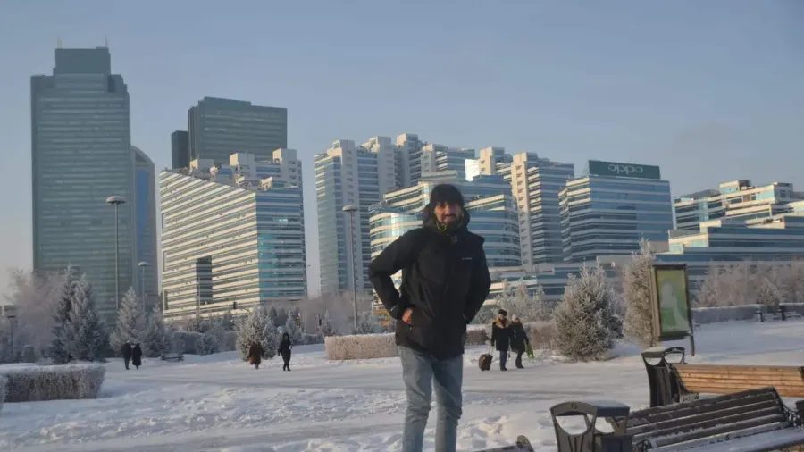 Viajero de pie en una calle nevada de Astaná con rascacielos modernos al fondo