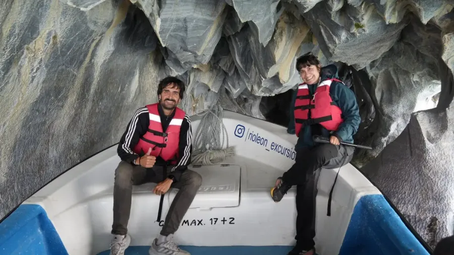 Sergio y Cris con chalecos salvavidas rojos en una lancha dentro de las Capillas de Mármol, rodeados de roca de mármol esculpida