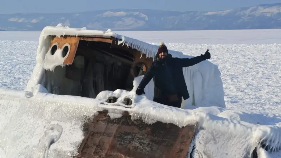 Viajero con el pulgar levantado junto a un vehículo cubierto de nieve