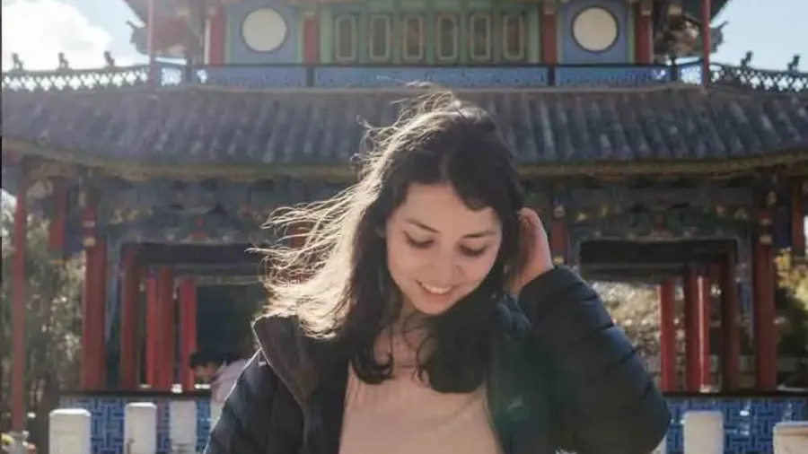 Joven viajera con el pelo al viento frente a un templo asiático de tejado tradicional