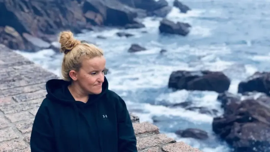 Retrato de una mujer con sudadera negra junto a las rocas de la costa