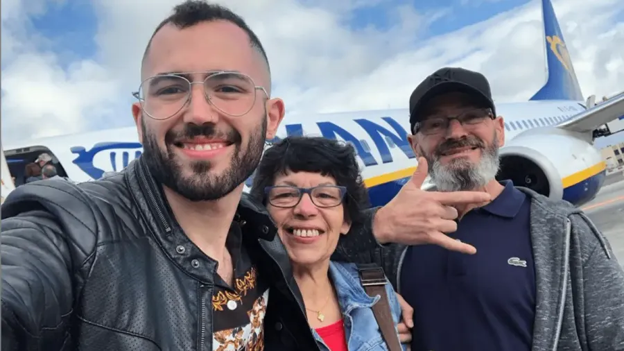 Tres personas haciéndose un selfie frente a un avión, una de ellas haciendo un signo con la mano