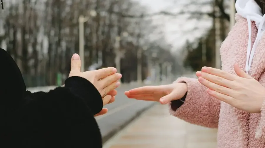 Dos personas conversando en lengua de signos en un paseo arbolado