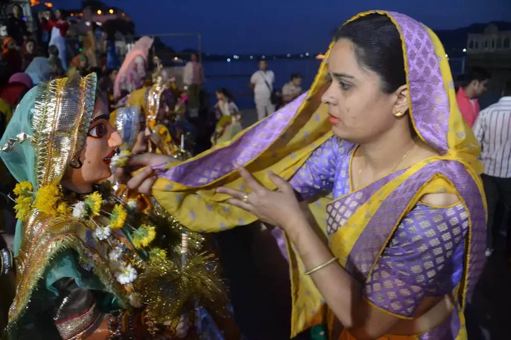 Al final de la procesión cada mujer deja su imagen de la diosa en la orilla del lago Pichola y le reza de rodillas pasándole una flor por su rostro