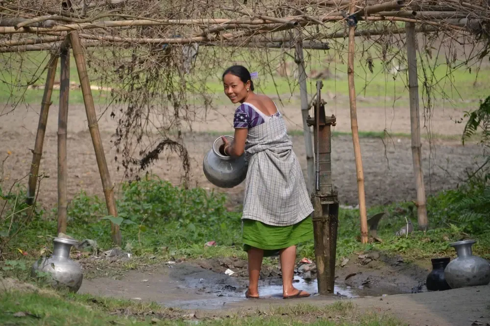 Mujer tribal llenando agua de la fuente