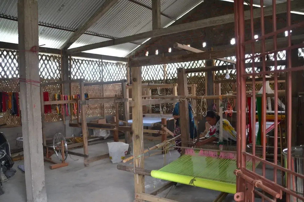 Mujeres de la cooperativa tejiendo con la máquina tradicional de Majuli