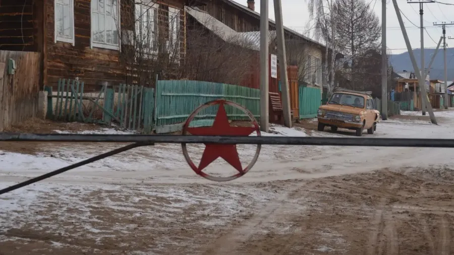 Calle de un pueblo de la isla de Oljón con casas de madera, una estrella roja y un coche antiguo