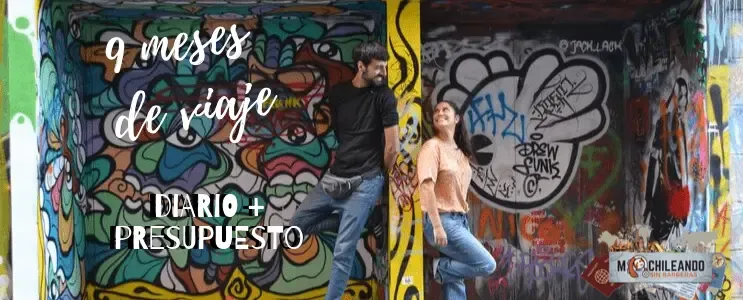 Pareja frente a un mural de graffiti con el texto «meses de viaje»