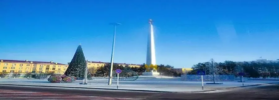 Obelisco y árbol de Navidad en una plaza nevada de Karaganda