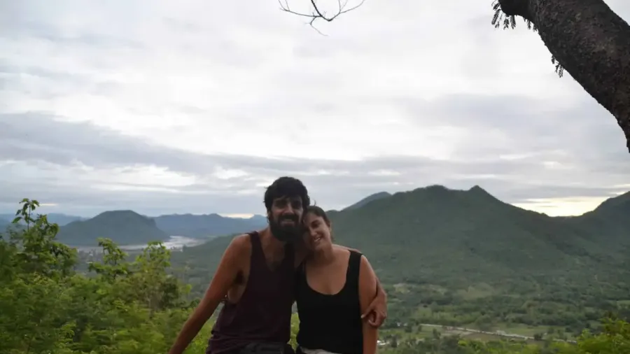 Pareja sonriendo en un mirador con montañas verdes al fondo