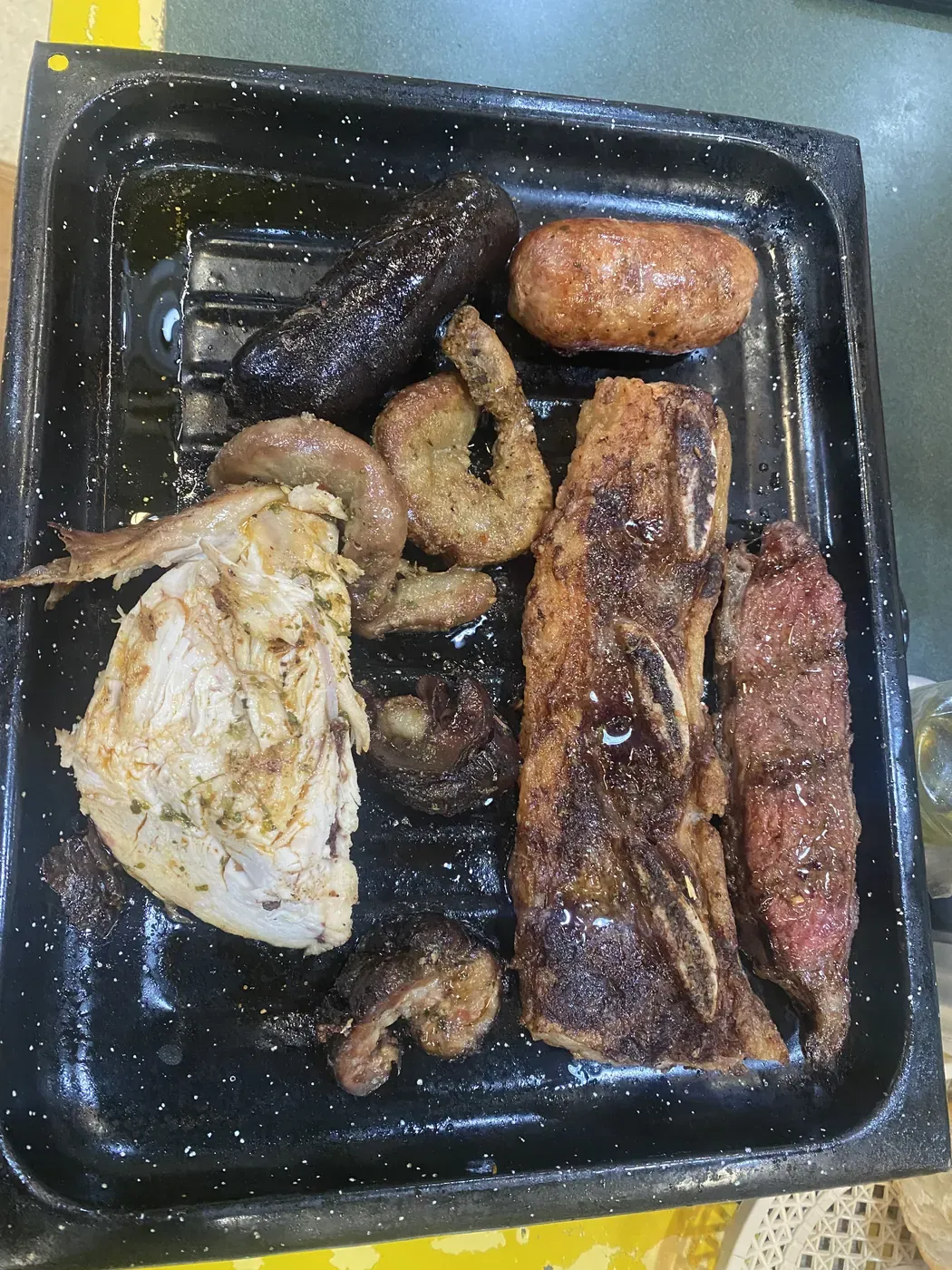 Bandeja con el asado del menú del día: morcilla, chorizo, pollo, costillar y otros cortes a la parrilla