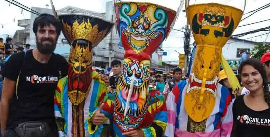 Tres máscaras de colores del festival Phi Ta Khon junto a un viajero