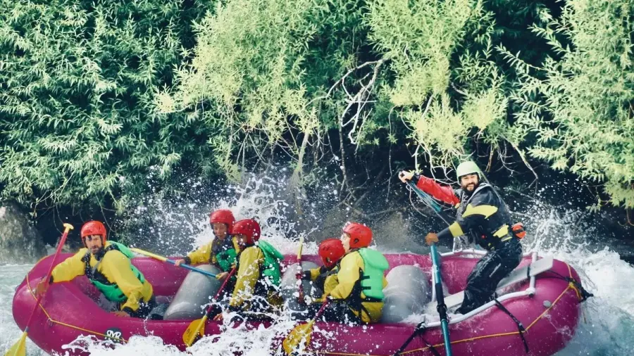 Una balsa de rafting con seis personas y un guía atravesando un rápido de aguas bravas junto a la vegetación del río Futaleufú