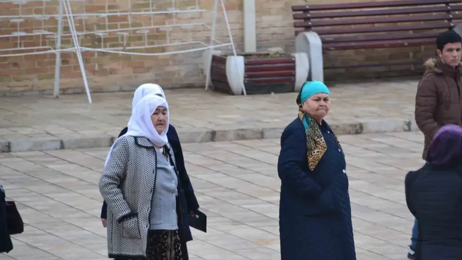 Mujeres locales con pañuelo conversando en una plaza de Uzbekistán