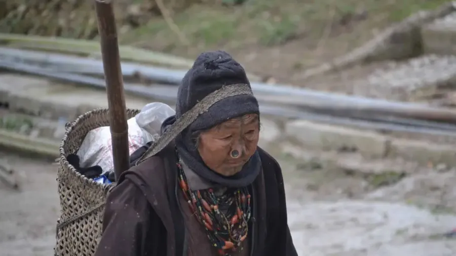 Mujer mayor cargando una cesta a la espalda en el noreste de India