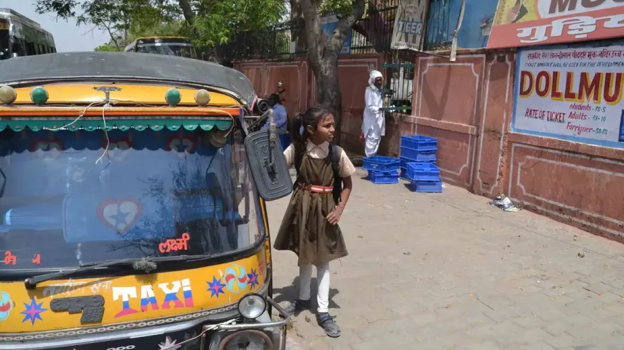 Rickshaw motorizado amarillo y negro con una niña en una calle de India